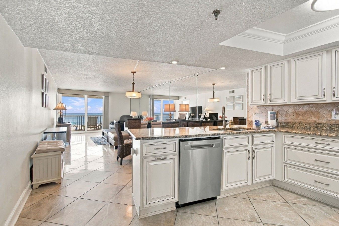 A spacious kitchen with a central island, white cabinetry, and a dishwasher.