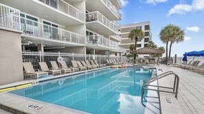Una piscina con una marca de profundidad de 1.8 metros, sillas de descanso y un edificio con balcones.