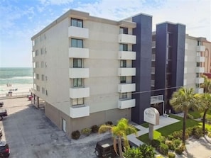 Un hotel de varios pisos con balcones, zona de estacionamiento y vistas a la playa.