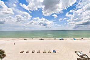 A beach with a clear sky, calm sea, and a few beach umbrellas.