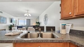 Una cocina moderna con un lavamanos doble, armarios de madera y encimera de granito.