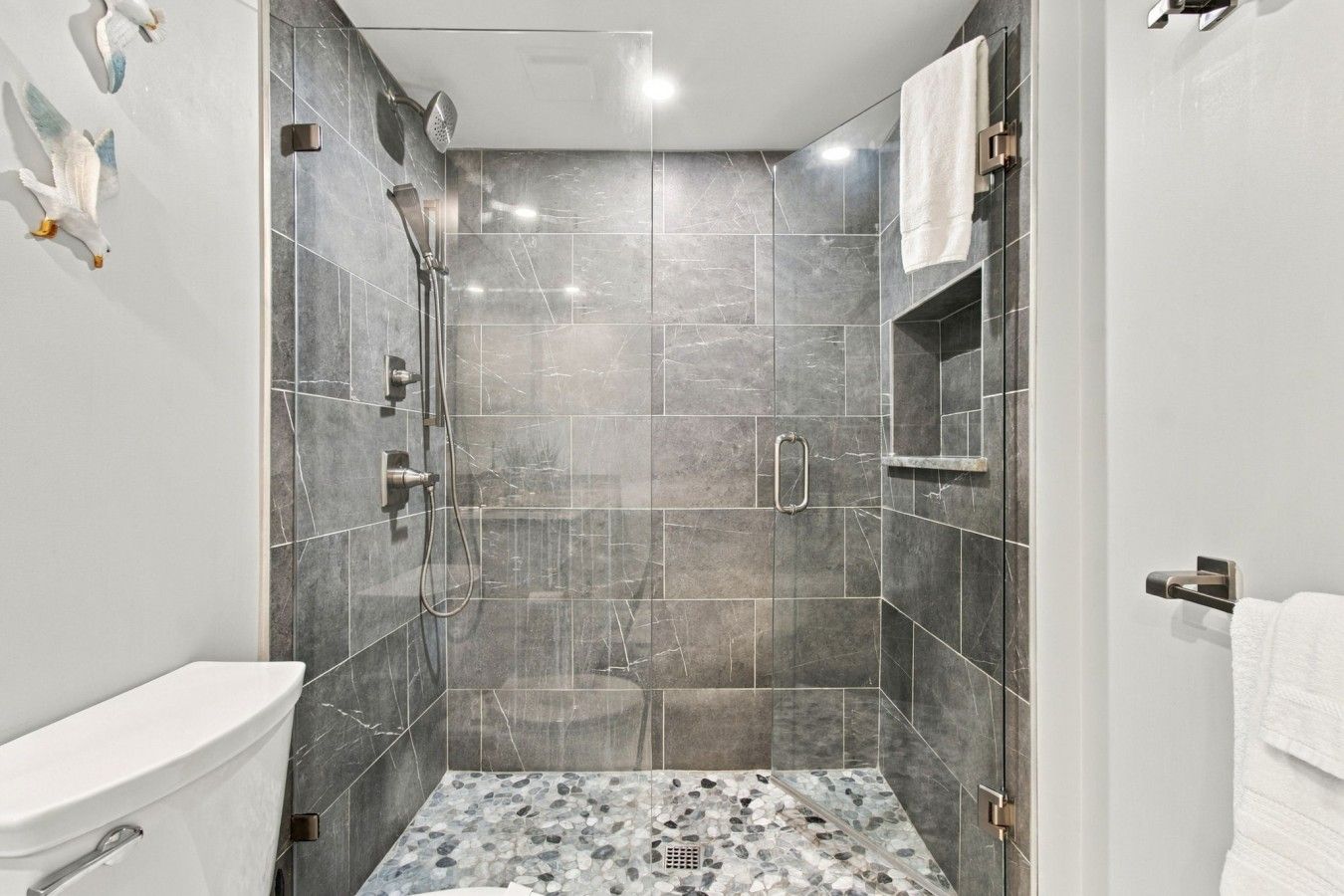 A modern bathroom with a shower, toilet, and a tiled floor.