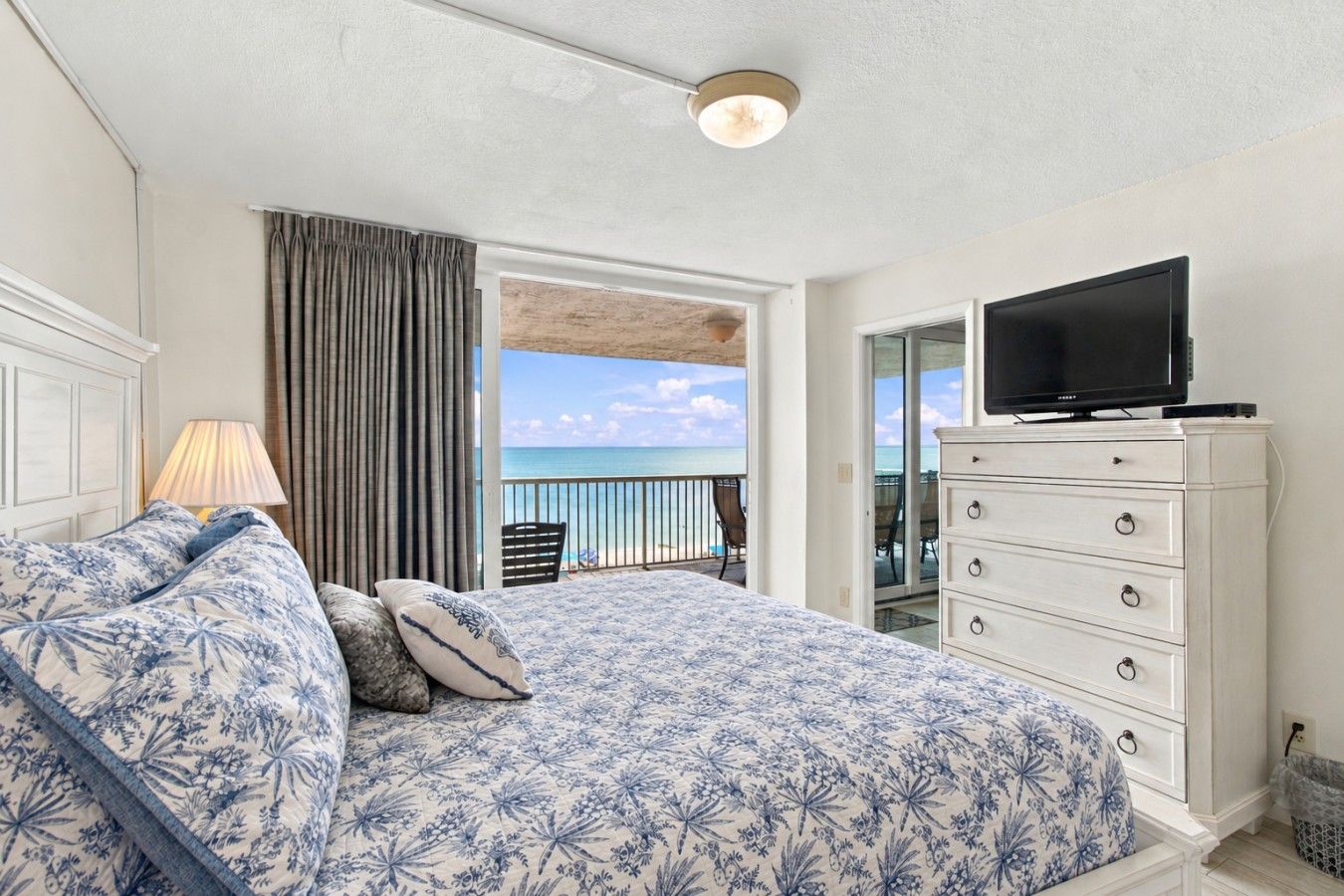 Une chambre à coucher avec un lit, une commode, une télévision et une vue sur l’océan.