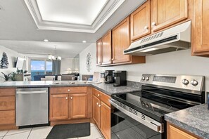 A modern kitchen with wooden cabinets, stainless steel appliances, and a view to the outside.