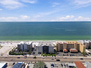 A beachfront hotel with multiple buildings, a parking lot, and a beach in the background.