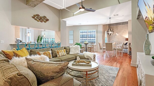 A spacious living room with a large sofa set, a coffee table, and a dining area with chairs and a table.