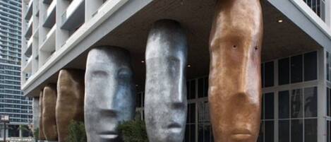 A modern building with large, abstract sculptures of human heads under a sloped roof.