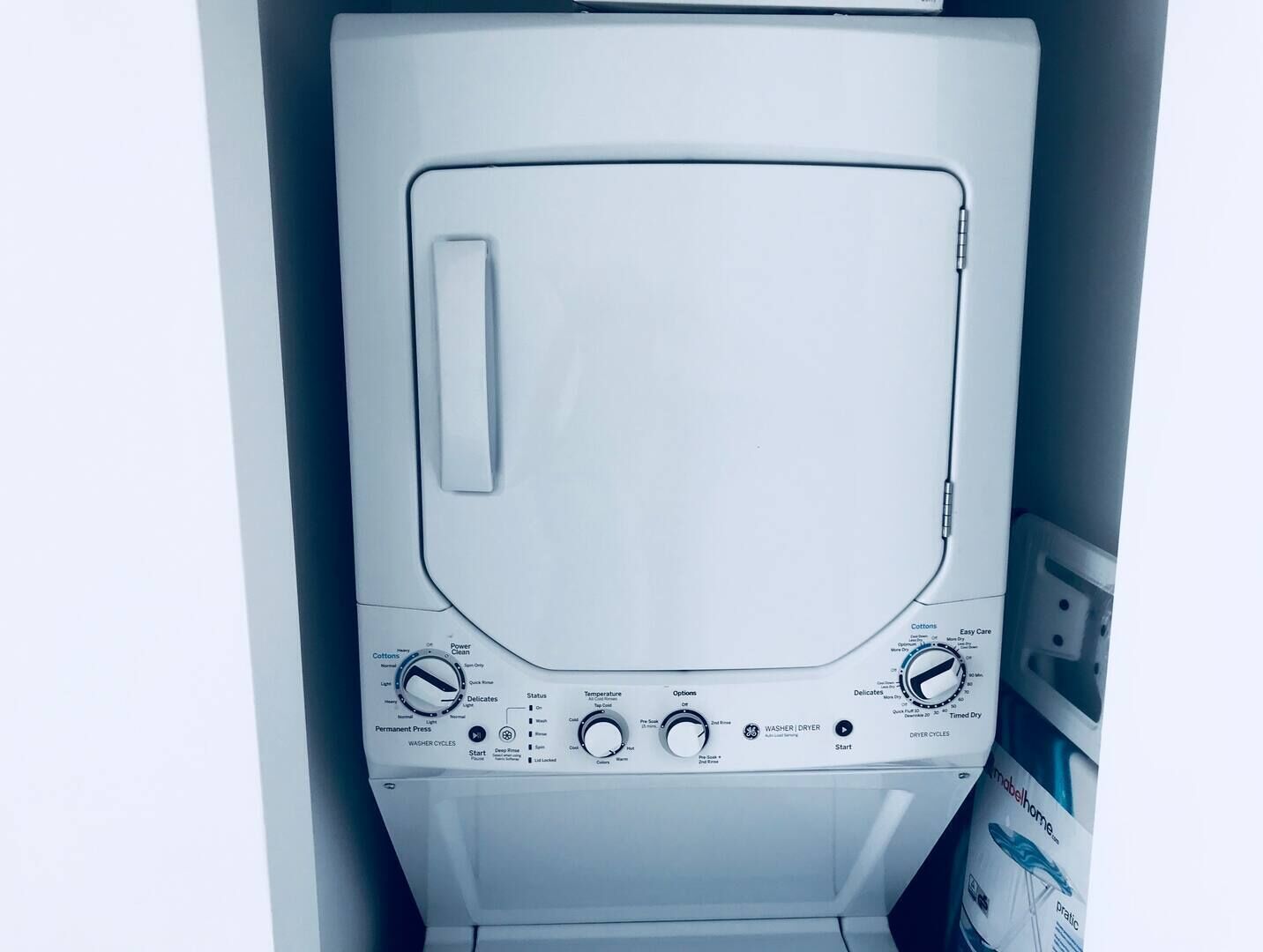 A front view of a white washing machine with control knobs, buttons, and labels for settings like "Cottons," "Power Clean," and "Delicates."