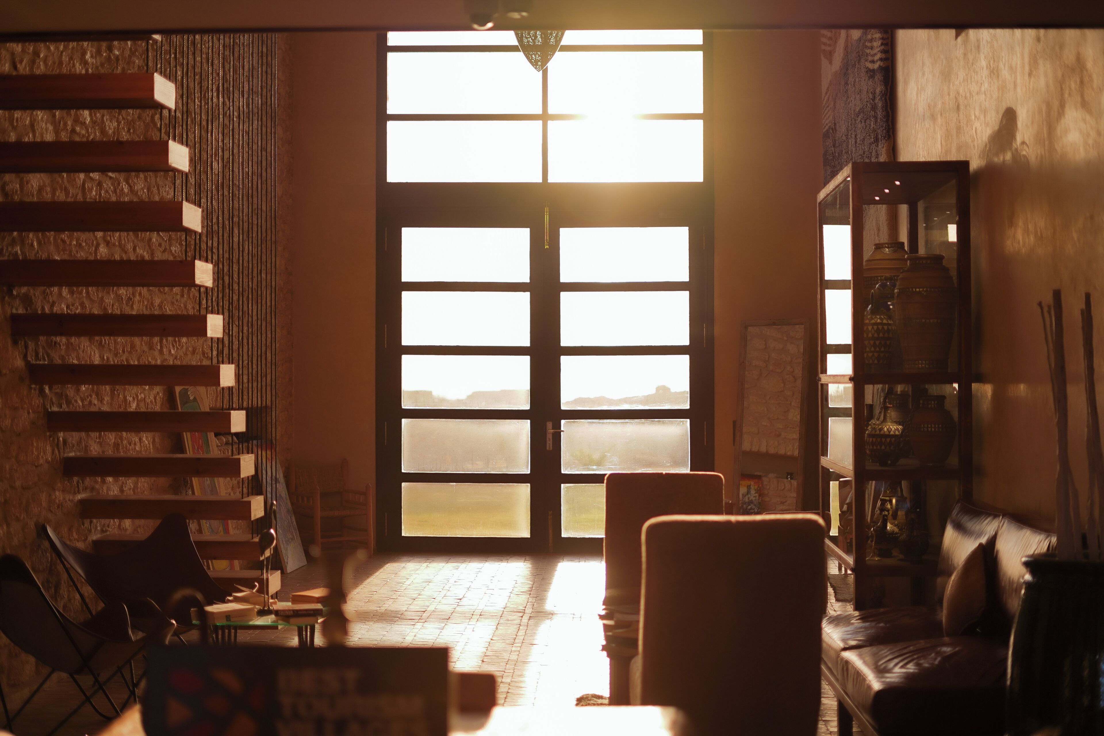A room with a staircase, a sofa, a table, and a bookshelf.