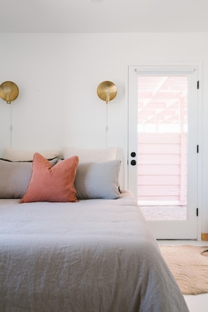 A bedroom with a bed, pillows, a door, and a light fixture.
