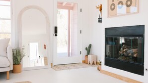 Een moderne woonkamer met een witte deur, een open haard en een grote spiegel.
