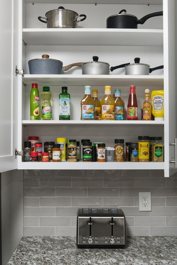Une cuisine dotée d’une étagère intégrée, servant de garde-manger, où sont rangées les huiles de cuisson, les vinaigres et les condiments.