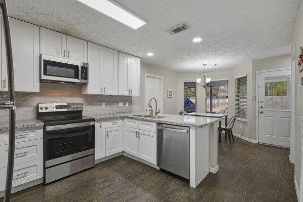 A modern kitchen with white cabinets, stainless steel appliances, and a granite countertop.