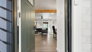 A hallway with a wooden floor, a green door, and a white wall with a textured pattern.