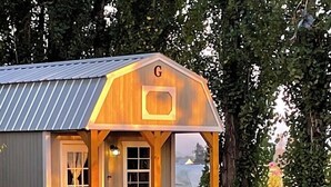 A small wooden cabin with a porch, a window, and a door. - Quiet Glamping Barn on a Working Farm with Fire Pit and Open Views (Lynden)