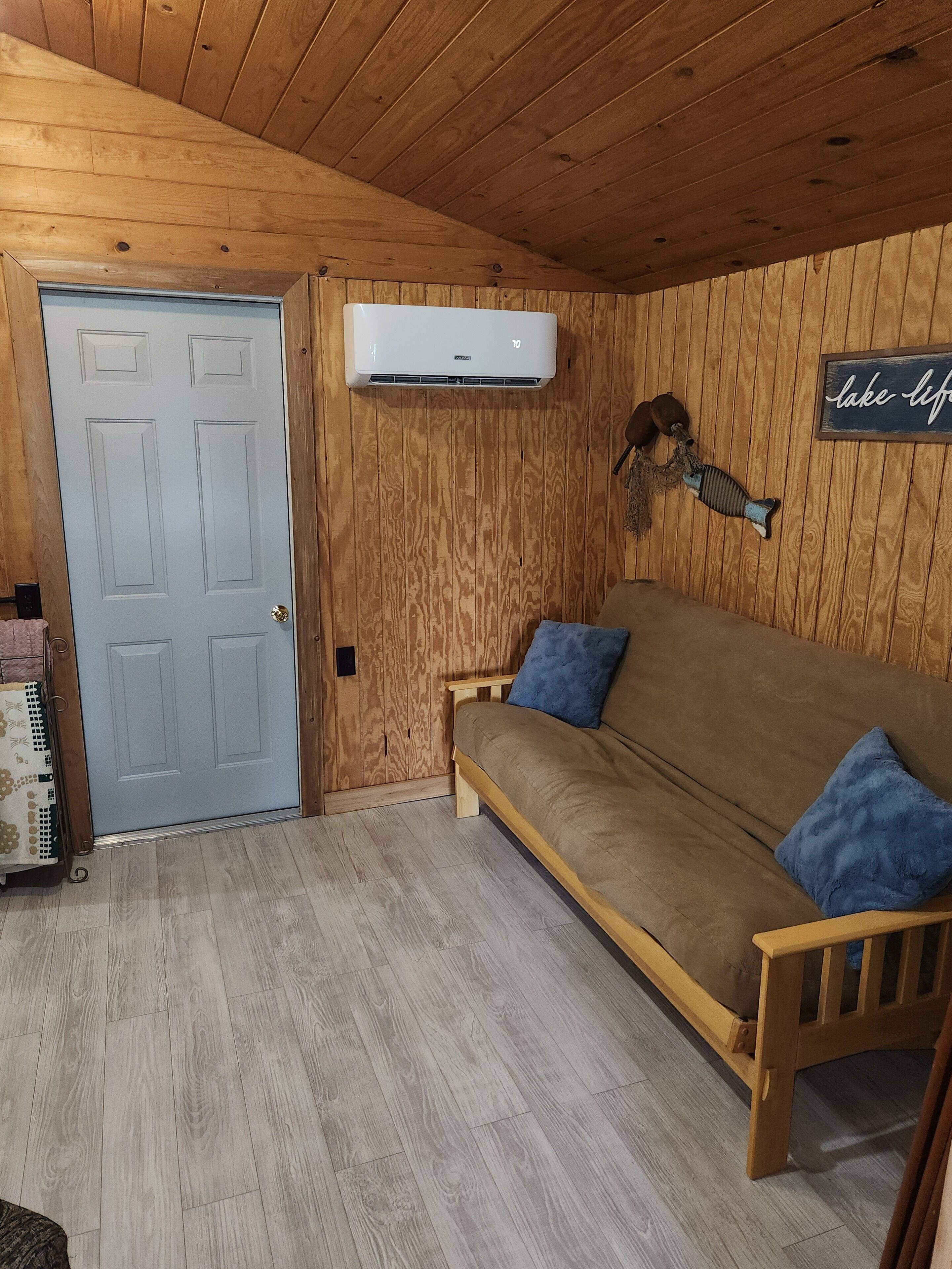 Un interior de madera con un sofá, una puerta y un equipo de aire acondicionado.