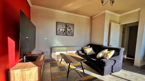 A modern living room with a sofa, a coffee table, a TV, and a radiator. - Private small house in Cork countryside [Springfiled] (Minane Bridge)