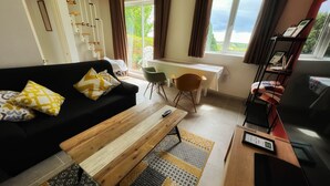 A living room with a black sofa, wooden coffee table, and a dining area with a table and chairs. - Private small house in Cork countryside [Springfiled] (Minane Bridge)