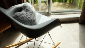 A modern room with a rocking chair, a glass door leading to an outdoor patio with white chairs and a table. - Private small house in Cork countryside [Springfiled] (Minane Bridge)