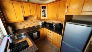 A compact kitchen with wooden cabinets, a built-in oven, a microwave, a coffee maker, and a refrigerator. - Private small house in Cork countryside [Springfiled] (Minane Bridge)