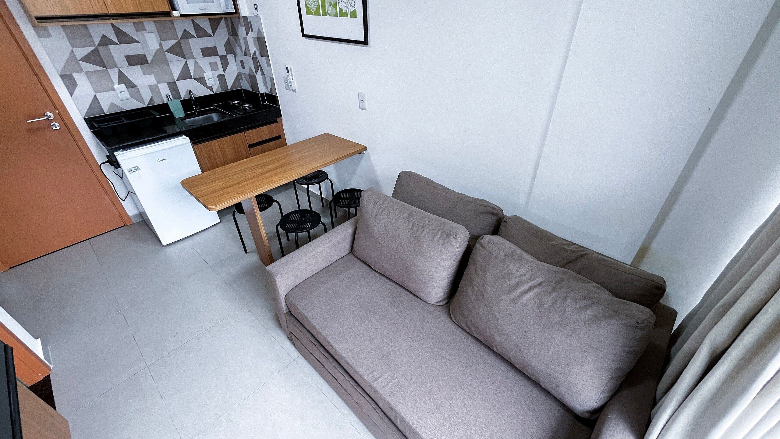 A compact living space with a kitchenette, a sofa, and a small dining table.