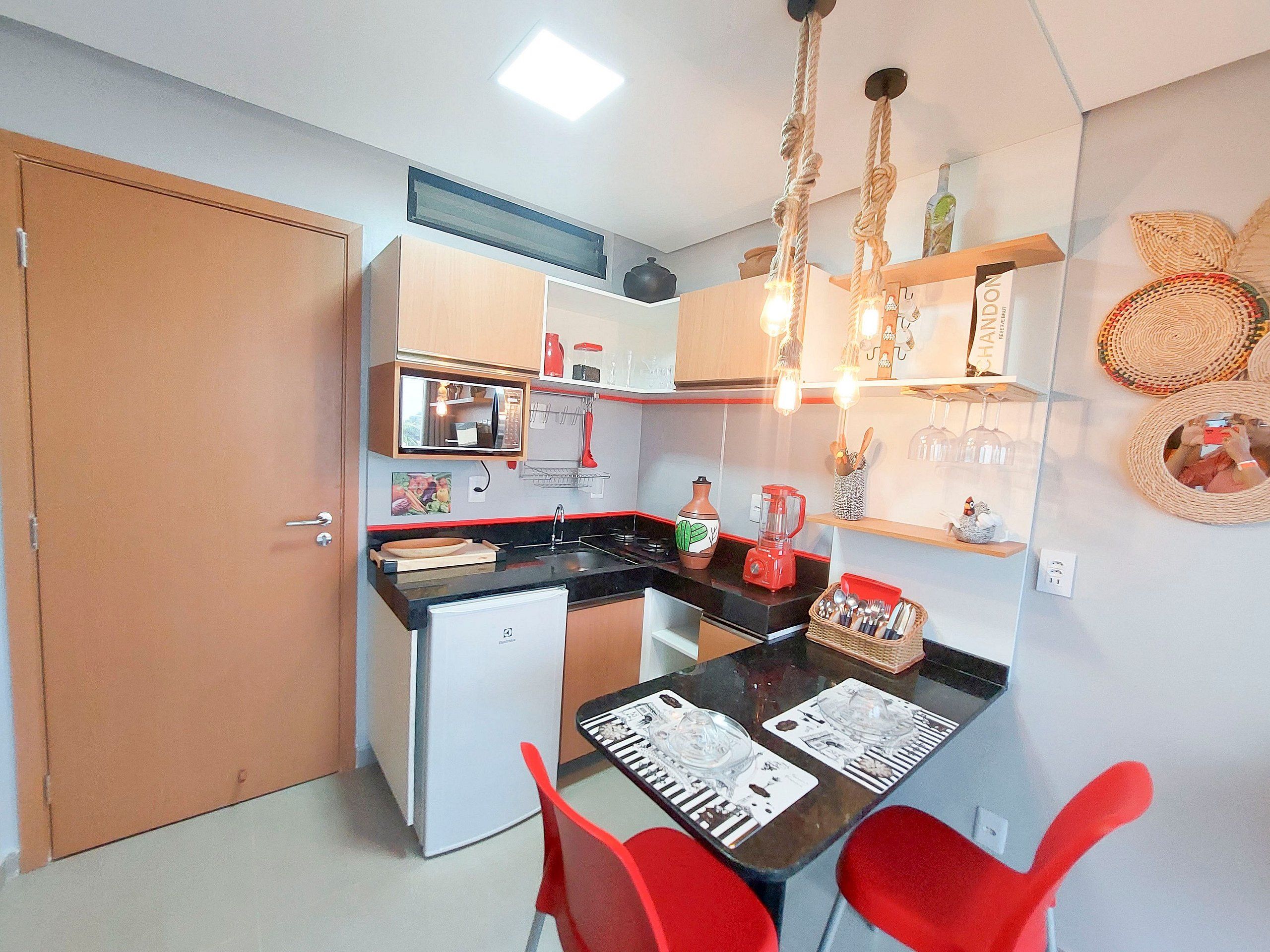 A compact kitchen with a refrigerator, stove, and a dining table with chairs.