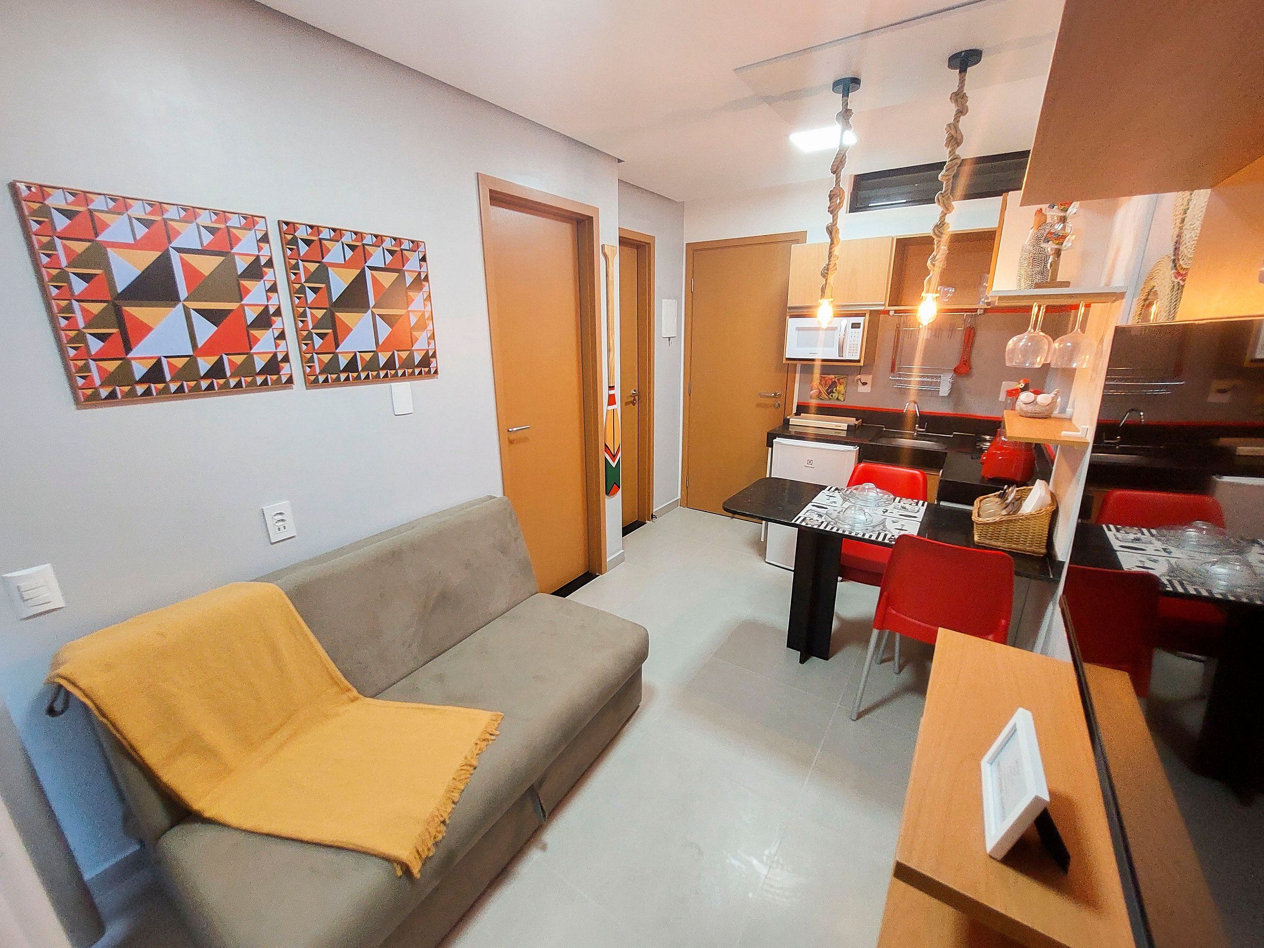Un espacio habitable compacto con sofá, mesa de comedor, sillas, zona de cocina y obras de arte en las paredes.