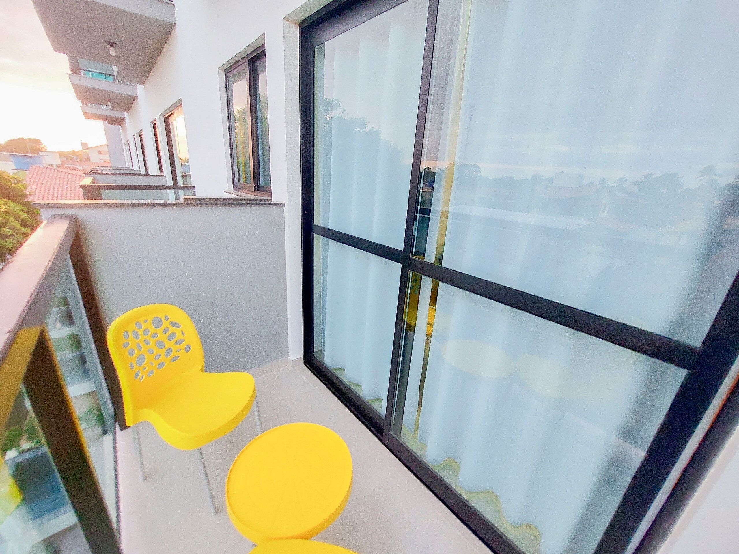 A balcony with yellow chairs and a large window.