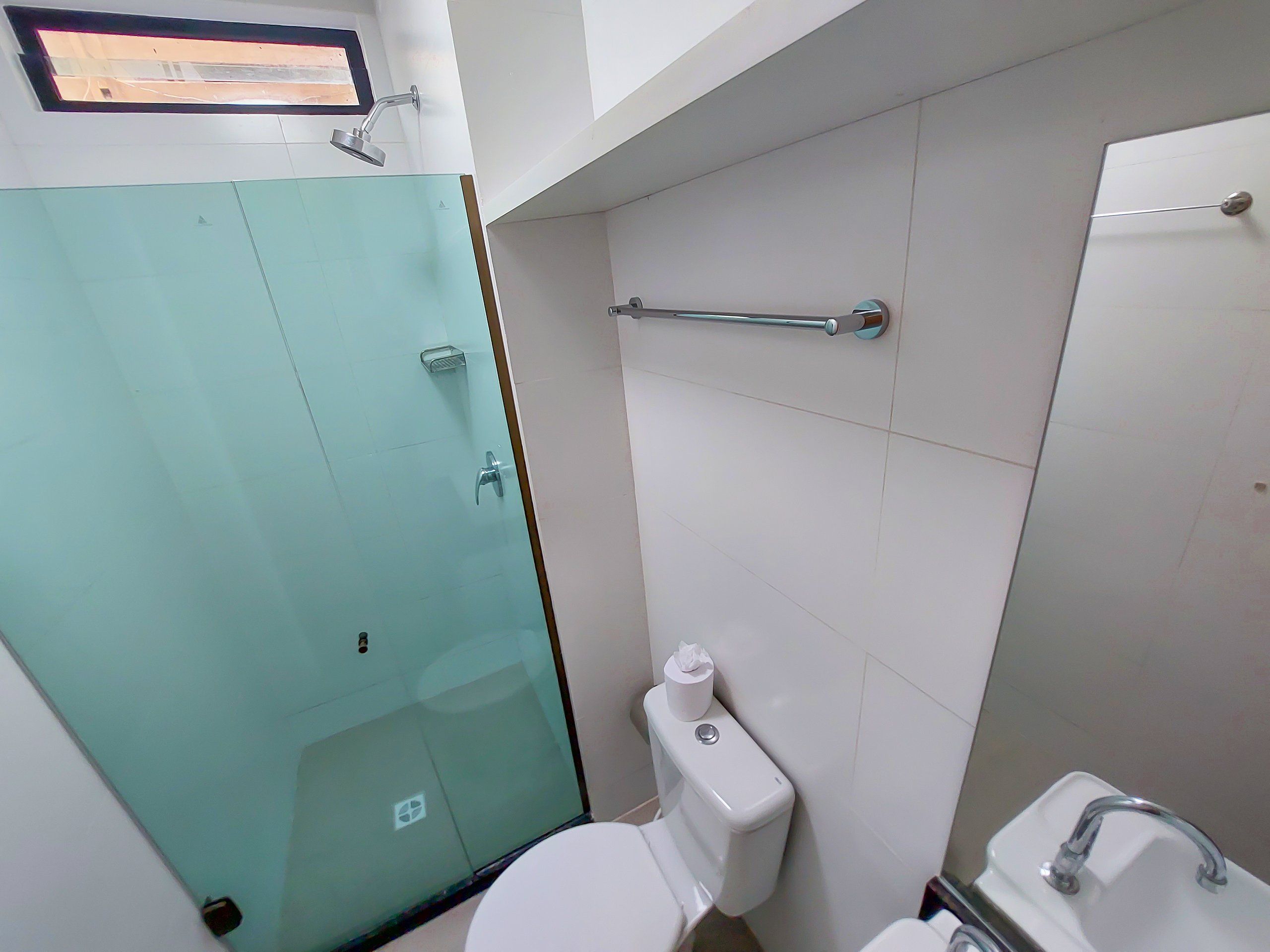 A bathroom with a glass shower enclosure, a toilet, a sink, and a towel rack.
