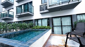 Un bâtiment moderne doté d’une piscine, d’un espace extérieur aménagé et de verdure.