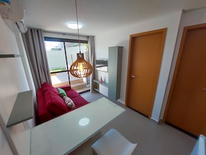 Quarto moderno com sofá, mesa, luminária pendente, guarda-roupa e uma porta.