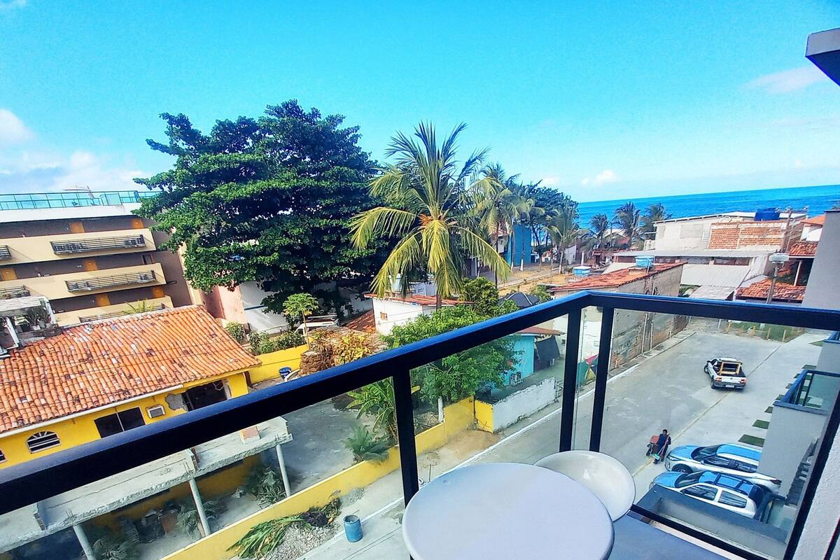 A balcony with two round tables and chairs, overlooking a street with buildings and a clear sky.