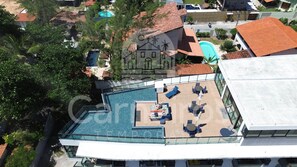 A rooftop pool area with lounge chairs and a glass balustrade. - Lindos Flats - Maraca Beach Residence II (Ipojuca)