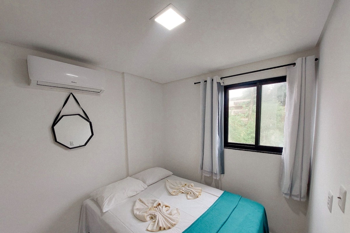A single bed with a teal bedspread and two towels arranged on it.