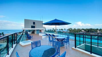 Una terraza en la azotea con piscina, mobiliario exterior y vistas al océano.