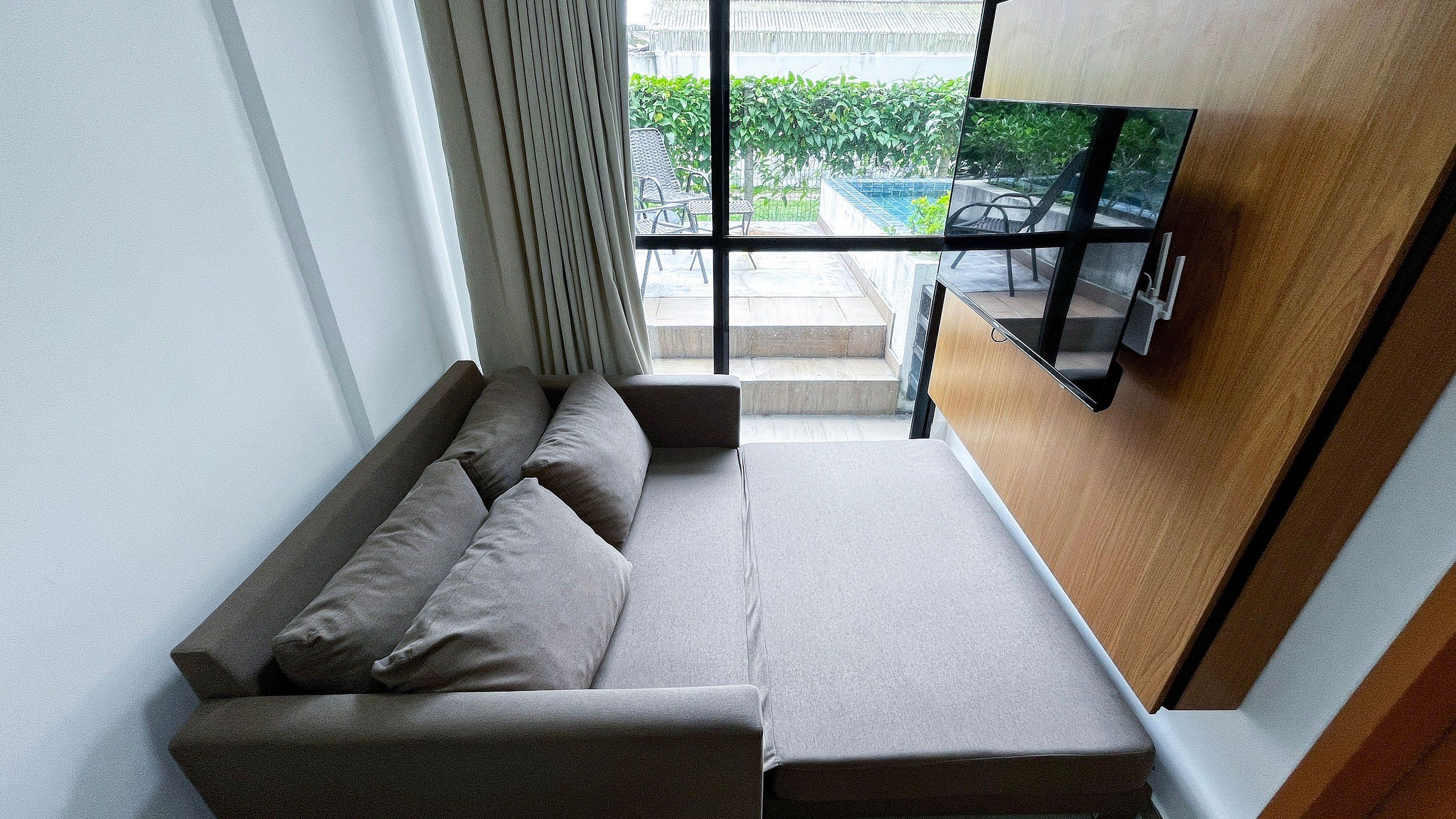 Eine Sitzecke mit einer Couch und einem Fenster mit Blick auf einen Garten.