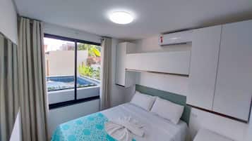 Quarto de hotel com cama, janela com cortinas, ar condicionado e vista para uma piscina.