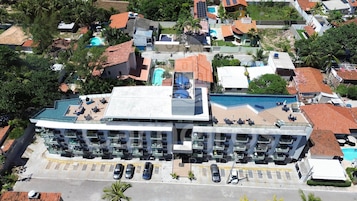 Ein Hotel mit mehreren Schwimmbecken, einer Dachterrasse und einem Parkplatz.