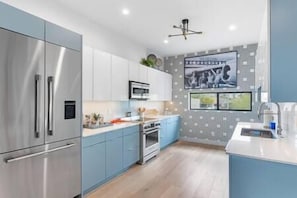 Una cucina moderna con elettrodomestici in acciaio inossidabile, mobili azzurri e un'ampia finestra.