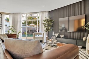 Uma sala de estar moderna com uma televisão grande, assentos confortáveis e vista para o exterior.