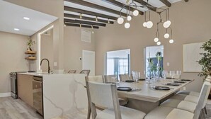 A modern kitchen with a central island, built-in appliances, and a dining area with a large table set for six. - Stunning 2 Story Villa with Pool (Wilton Manors)