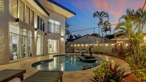 A modern house with a swimming pool, outdoor seating, and a well-lit patio area. - Stunning 2 Story Villa with Pool (Wilton Manors)