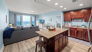 A modern kitchen with wooden cabinets, a granite countertop, and a built-in island. - Gulf views! Spacious with 2 King beds, Bunk Room | 5 Pools (Panama City Beach)