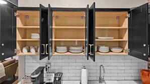 A kitchen with open cabinets displaying plates and cups, a coffee machine, and a sink. - Penthouse Loft Downtown Huge Unit (Birmingham)