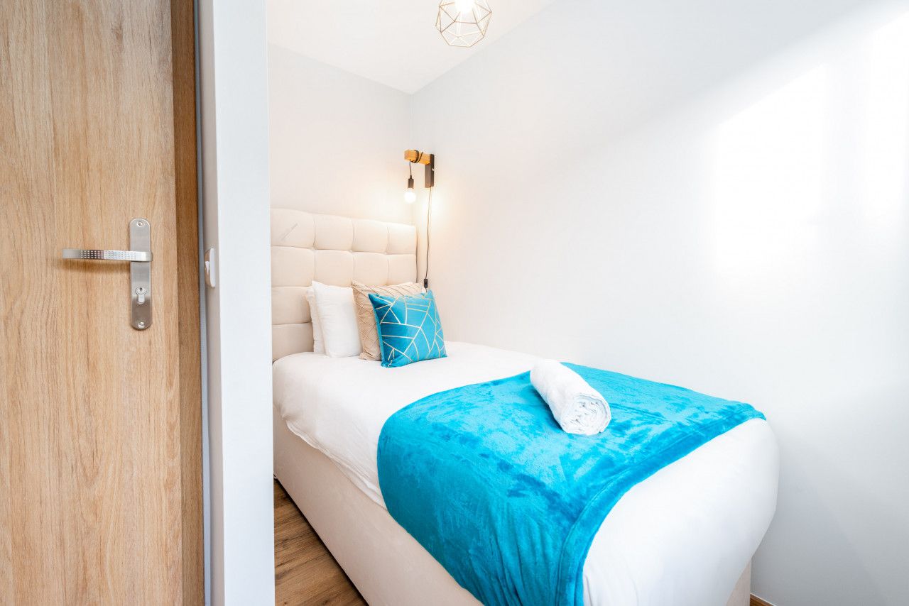 Un dormitorio moderno con cama, lámpara de noche y puerta de madera.