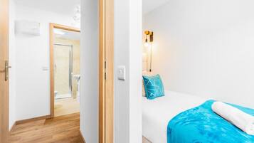 Ein Hotelzimmer mit Holzboden, einem Bett mit blauer Decke und blauem Kopfkissen sowie einer Wandleuchte.