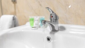 A bathroom sink with running water, a glass of soap, and a towel. - Brand New - Two Bed - Parking - Stourbridge (West Midlands)