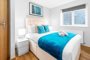 Une chambre à coucher avec un lit, des tables de chevet, une fenêtre et un tableau au mur.