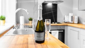 En flaske Prosecco vin på en køkkenbord med et glas.