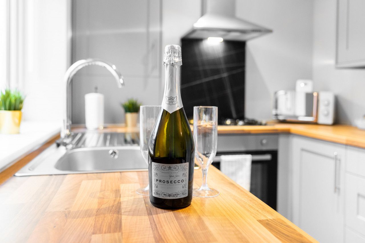 Eine Flasche Prosecco auf einer Küchenarbeitsplatte mit einem Glas.
